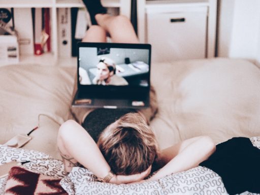 woman lying on bed while watching tv