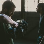 man holding camcorder with man near wall