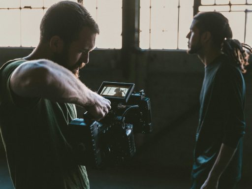 man holding camcorder with man near wall