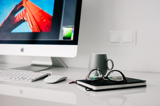 Nette thuiswerkplek met monitor, lamp en geordende kabels op een houten bureau