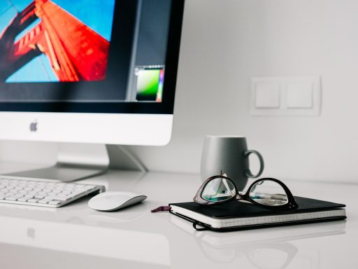 Nette thuiswerkplek met monitor, lamp en geordende kabels op een houten bureau